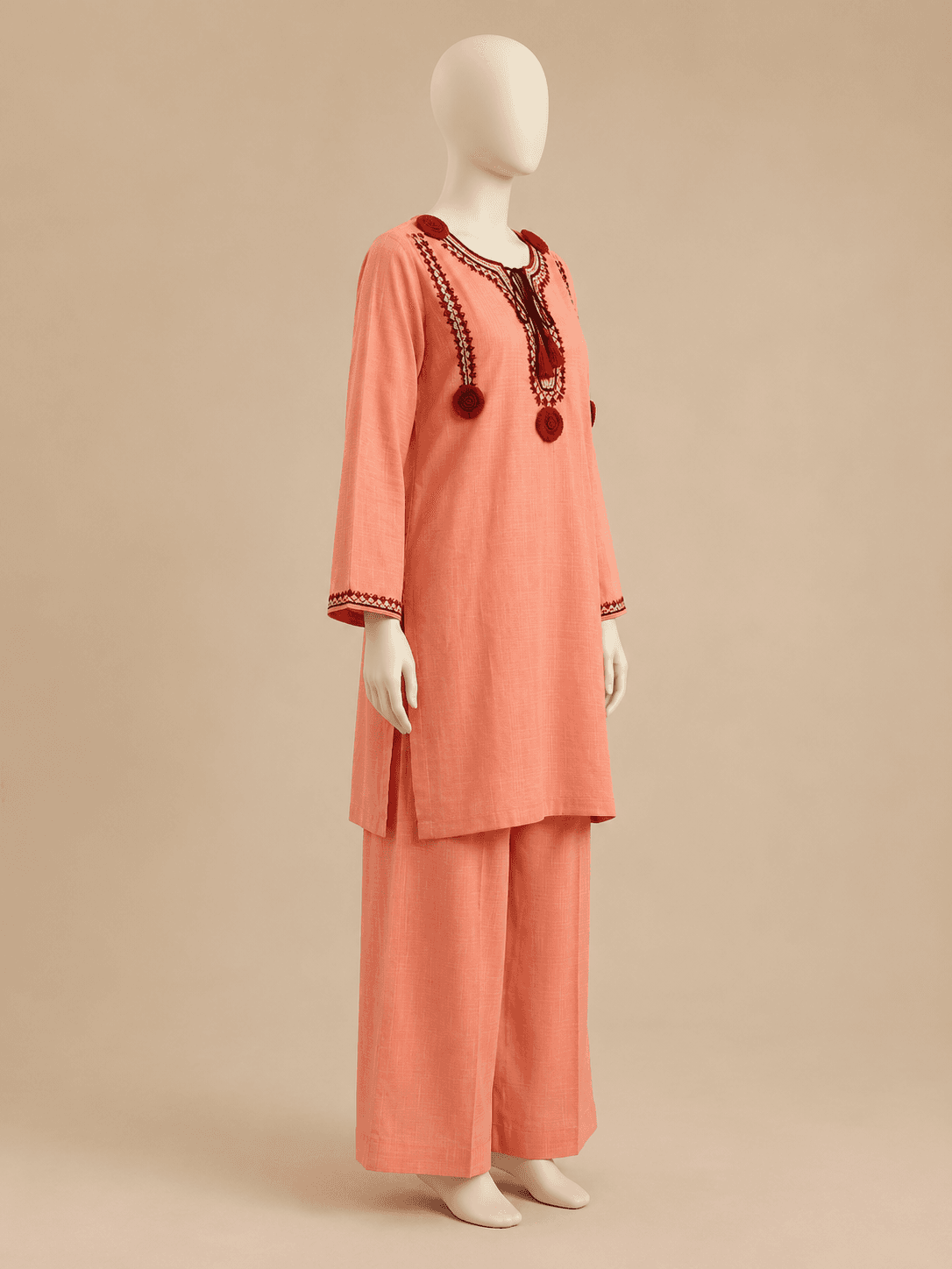 Coral embroidered kurta set, side profile against a warm backdrop